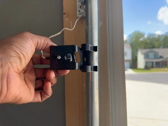 How to Align Garage Door Sensors: The Complete Troubleshooting Guide Hand adjusting a garage door safety sensor mounted on a track bracket