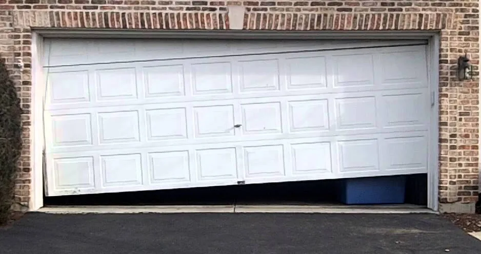Garage Door Safety: The Complete Guide for Utah Homeowners (2026) Damaged garage door with bent panels and a gap at the bottom showing why garage door safety matters for homeowners