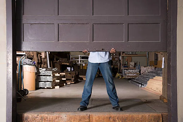Garage Door Won't Stay Open? Causes, Fixes, and When to Call a Pro Person holding up a garage door that will not stay open on its own